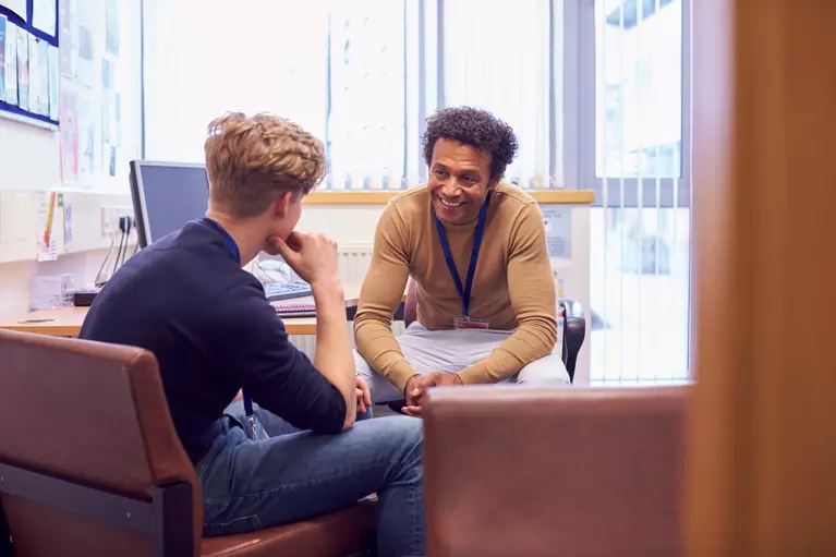 Teacher talking with a student in his office. 